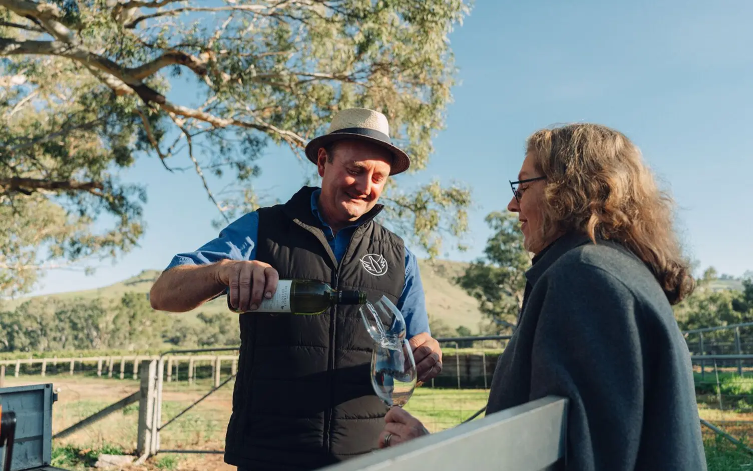 Winemaker pouring a glass of whine to another person